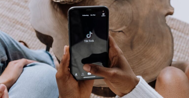 Close-up of hands holding a smartphone displaying the TikTok app interface on a wooden surface.